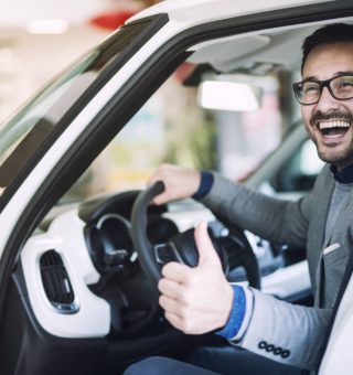 Homem em um carro sorrindo para câmera