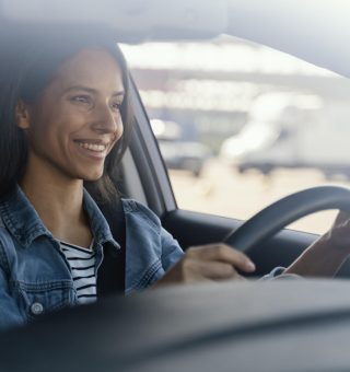 Mulher sorrindo enquanto dirige